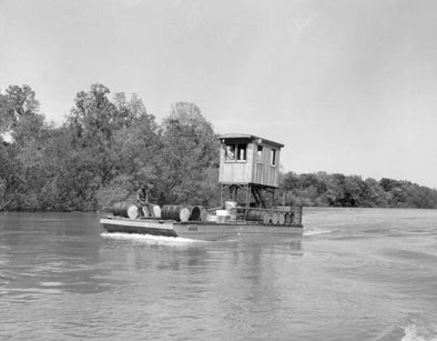 A flat boat carries barrels of tupelo honey on the Apalachicola River - Gulf County, Florida.