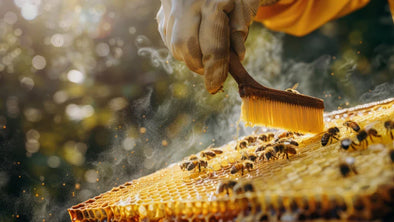 A beekeeper wearing a glove brushes honeycombs with a brush, surrounded by bees. Smoke rises as the beekeeper works, with a blurred green background featuring bokeh effects.
